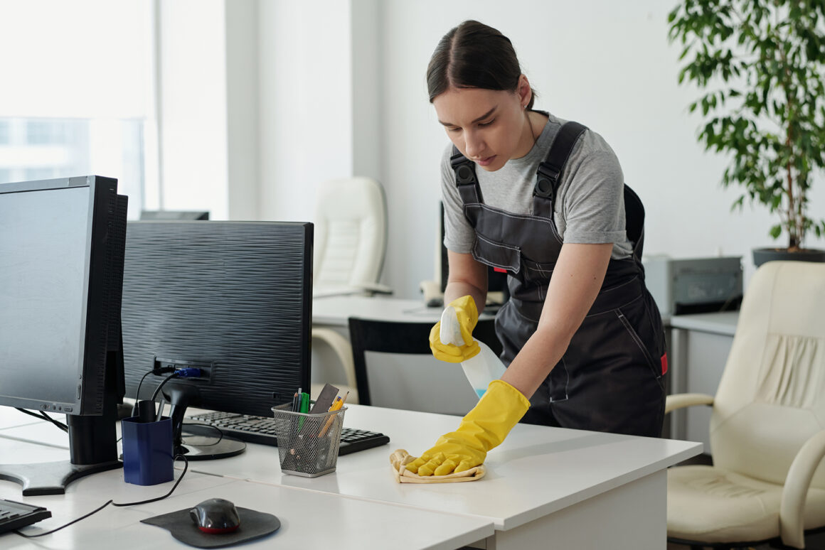 Young female staff of cleaning service company wiping desk in openspace office Commercial Premises Cleaning